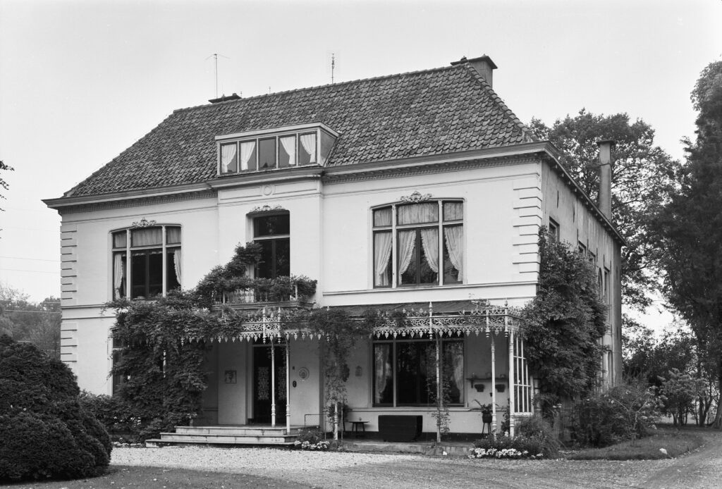 Een witte villa met twee verdiepingen een veranda voor het huis