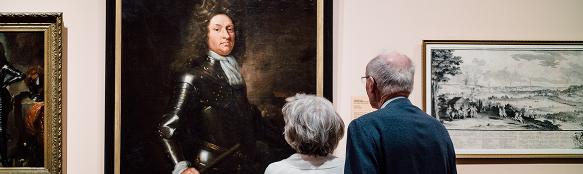 Twee mensen krijken naar het schilderij van een man die terug kijkt