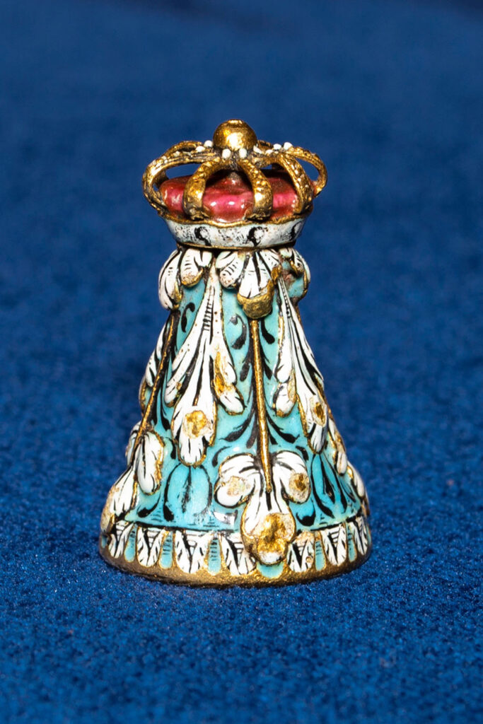 Rond torentje met een aqua achtergrond en daarop witte gestileerde blad en bloemmotieven. Bovenop een kroontje.