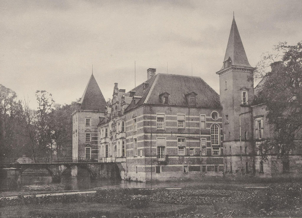 Een kasteel waarbij in de muren met strepen hardsteen en ook het deel in de gracht van hartsteen is. In de voorgevel zitten twee erkers, ook van hardsteen. Linksachter een brede lage toren, rechtsvoor een spitse hogere. Links de brug over de gracht.