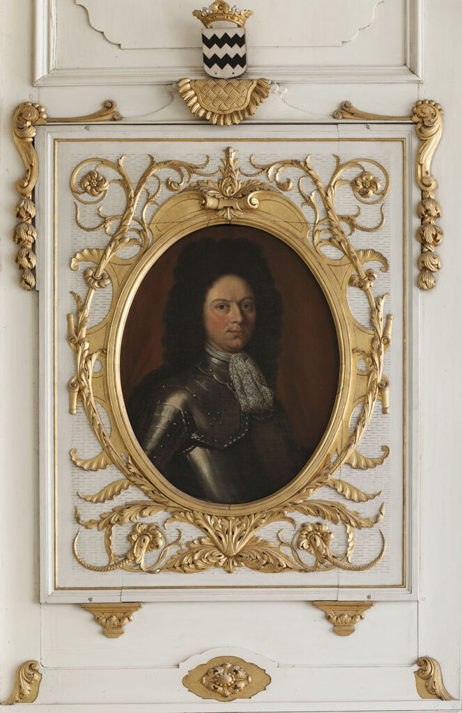 Een buste portret van Portret van Godard Adriaan van Reede van Herreveld. Hij staat naar rechts gekeerd en kijkt naar rechts. Hij staat voor een donkere achtergrond. Godard draagt een kuras met een jabot en een donkere pruik met krullen. Het schilderij is verwerkt in de lambrisering van de eetkamer: een withouten lambrisering rondom het ovale schilderij is met goudkleurige ranken van planten een lijst nagemaakt. Boven het portret het Van Reede wapen.