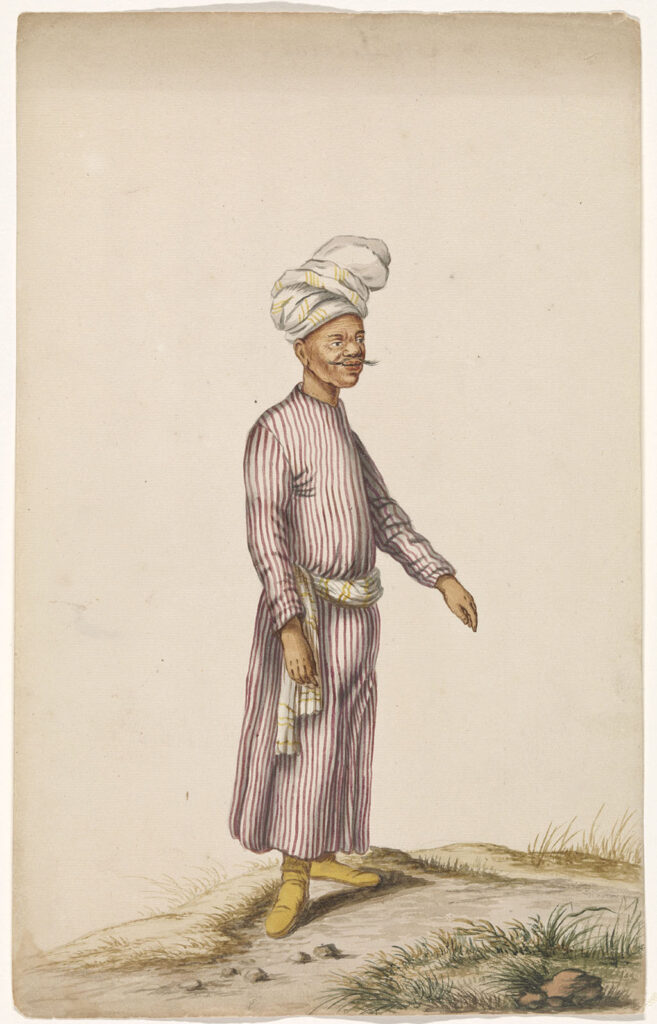 Een man met leren laarzen, een paars-wit gestreepte kaftan, met een geel/witte sjaal om zijn middel. Op zijn hoofd draagt hij een wit/gele tulband.