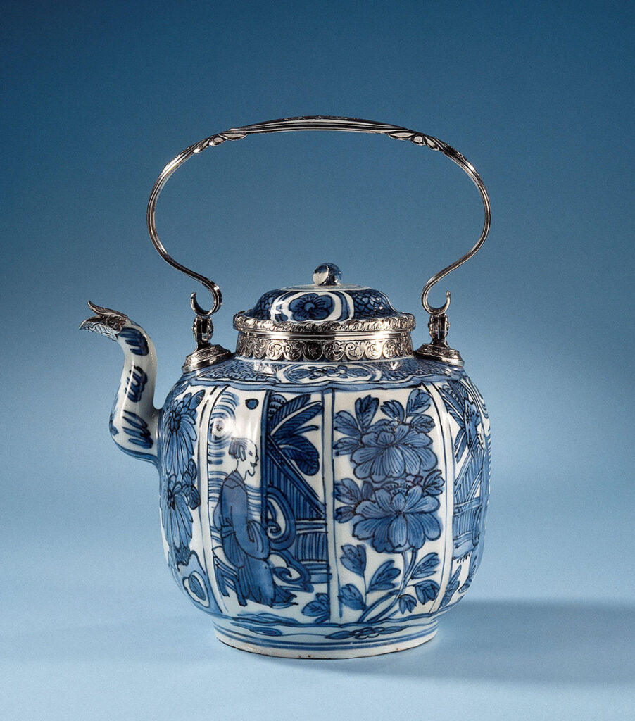 Theepot van porselein met een geribd, bolvormig lichaam en S-vormige tuit, beschilderd in onderglazuur blauw. De wand is verdeeld in vakken met afwisselend een bloeiende plant (chrysant, pioen) en een persoon zittend op een omheind terras; de schouder met een band servetwerk afgewisseld met een bloem in een cartouche. Voorzien van een 19e-eeuws zilveren montuur en handvat door Arnoldi & Wielick, Amsterdam 1850. Kraakporselein.