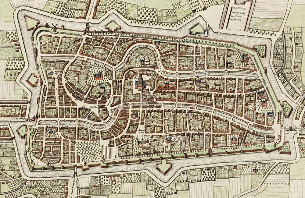 Een grijs en wit gekleurde kaart van de stad Utrecht in de 17de eeuw, van bovenaf afgebeeld. De stad is in de vorm van een liggende rechthoek en wordt omringd door de verdedigingswallen met aan de twee korte zijden de bastions in de vorm van pijlen met een korte poot. Aan de bovenkant zijn twee pijlen, aan de onderkant een in het midden. Buiten de stad zijn vierkanten en rechthoeken van verschillende grootten getekend met verschillende soorten arceringen. Binnen in de stad vallen de twee wateren die de stad van links naar rechts doorkruisen op, Van links beginnend, stromen ze redelijk recht, vanaf het midden naar rechts wat meer naar buiten gebogen. In de stad zijn kleine rechthoeken en vierkanten getekend met daarin kleine rechthoeken, voorstellend de huizen. Iets boven het midden maakt het bovenste water een bocht om een gebouw heen.