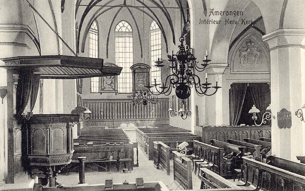 Zwartwit foto van het interieur van een kerk. Rechts tegen een pilaar de preekstoel, dan een kroonluchter. De kerkbanken staan eromheen gegroepeerd. We kijken door naar het koor van de kerk. Daar hangen rouwborden. Rechts in de zijbeuk een hogere kerkbank met daarachter een ruimte waar een gordijn voor hangt.