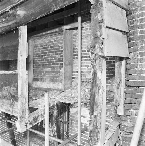 Zwartwitfoto van de constructie van het duifhuis tegen de muur.