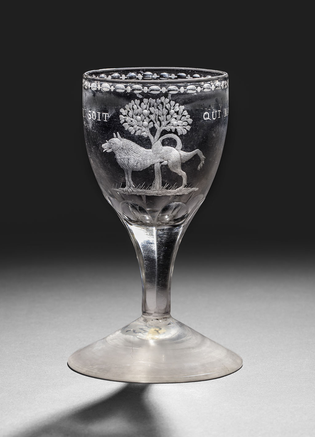 Kelkglas met daarop gegraveerd een oranjeboom waar een keeshond tegenaan plast.