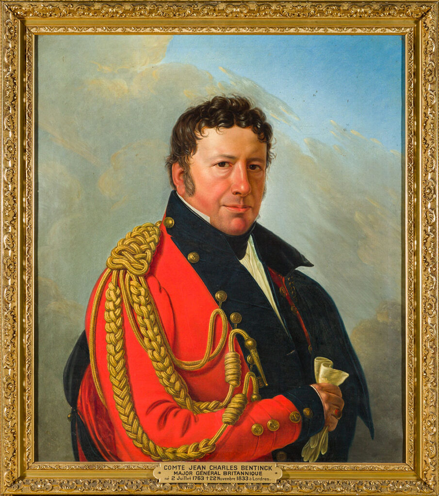 Halflengte portret van een man met korte donkere krullen, donkere ogen en bescheiden bakkebaarden. Hij draagt een rode uniformjas met zwarte revers, gouden tressen en gouden knopen. In zijn rechterhand heeft hij een paar witte handschoenen.