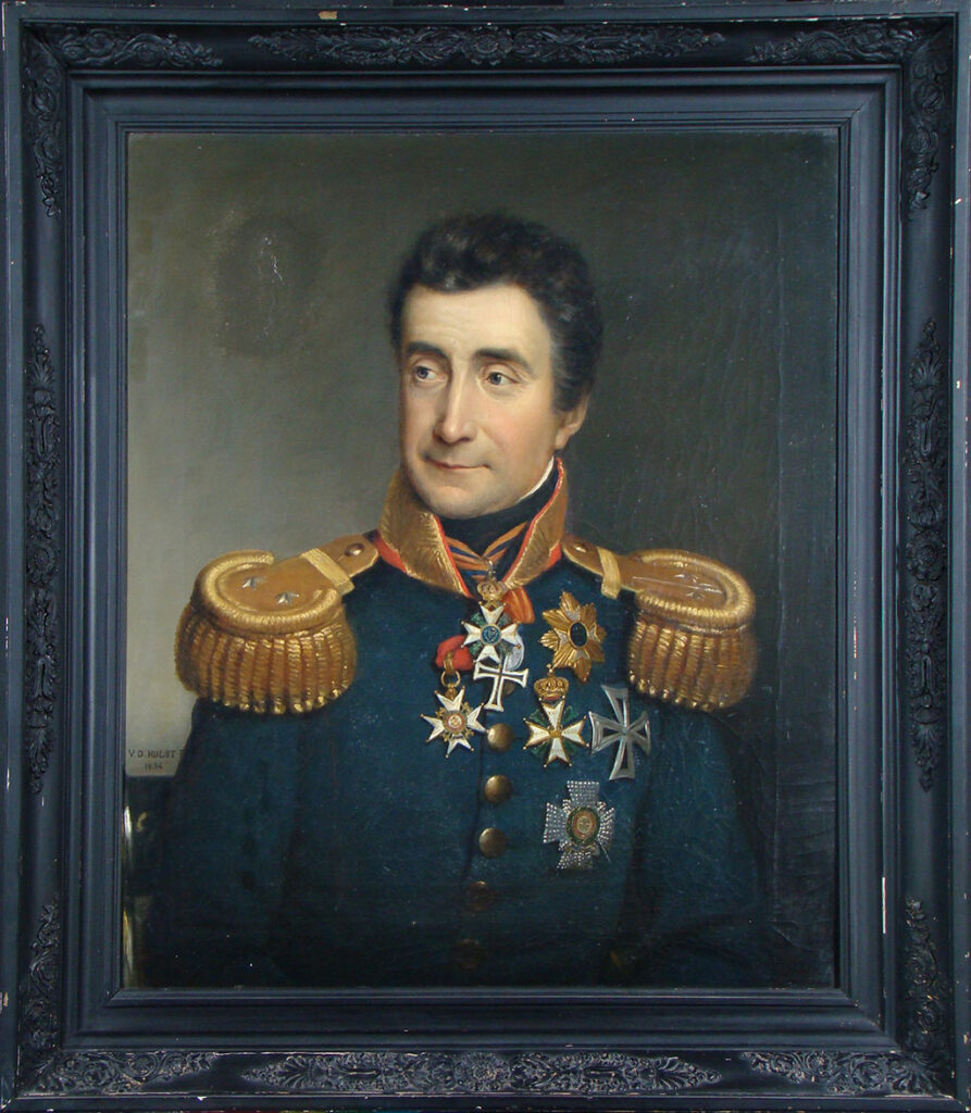 Een vriendelijk ogende man met donker kort haar, licht grijzend aan de slapen kijkt naar rechts. Hij dracht een uniform met forse gouden epauletten en een hoge rechte gouden kraag. Om zijn nek en op zijn uniform heeft hij diverse medailles, ere- en ordetekens.