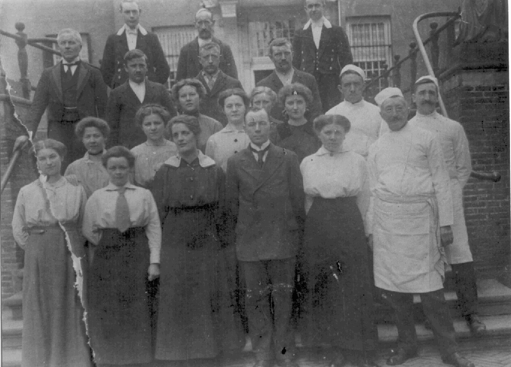 Een verzameling van mannen en vrouwen op de bordestrap van kasteel Amerongen. De dames dragen allemaal een lange rok, de mannen zijn verschillend gekleed: van wit met schort en mutsje, tot livrei.