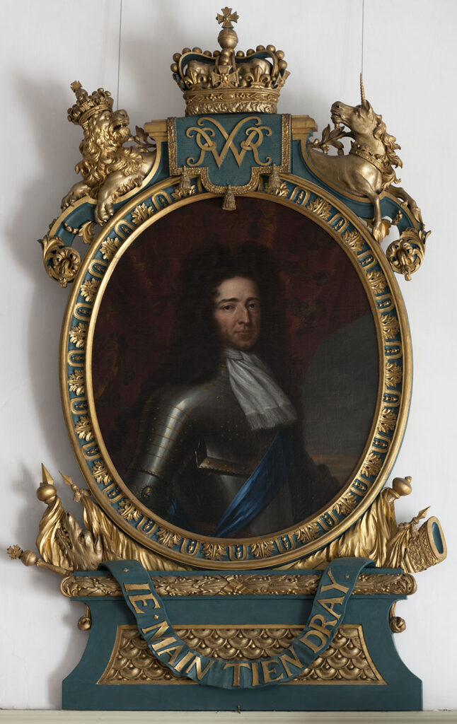 Ovalen portret van een man met een grote bos donkere krullen en een stevige neus. Hij draagt een harnas met een witte sjaal en een blauwe sjerp. De lijst is zeer bewerkt in blauwgroen met goud. De ovalen lijst heeft een moties, onder het ovaal vaandels, vlaggen, een hond, een kanon en een scepter, daaronder een soort pedestal met daaroverheen een band met de tekst "IE MAIN TIEN DRAY". Midden boven een kroon met daaronder het monogram voor Willem / William Rex. Links een gekroonde leeuw en rechts een eenhoorn.