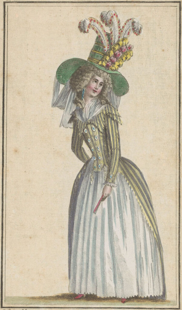 Staande vrouw gekleed in een 'demi-redingote' met paars/geel strepenmotief, middenvoor dichtgeknoopt. Om de hals een fichu. Accessoires: 'chapeau à la Tarare', waaier.