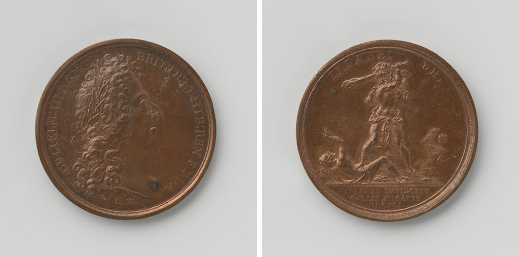 Twee kanten van een penning. Links de kop met de buste van Willem III: een man met een stevige haakneus en lange krullen. Op zijn hoofd zit een lauwerkrans. Aan de andere kant staat Hercules die met zijn knuppel Ierland verslaat terwijl Frankrijk vlucht.