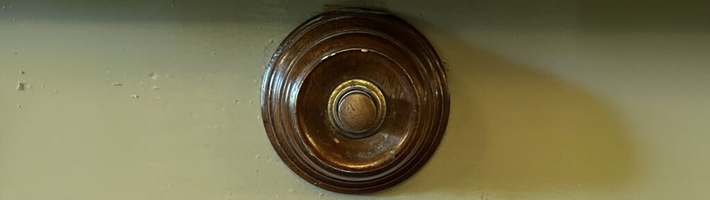 Een ronde houten houder met daarin een ronde drukknop.