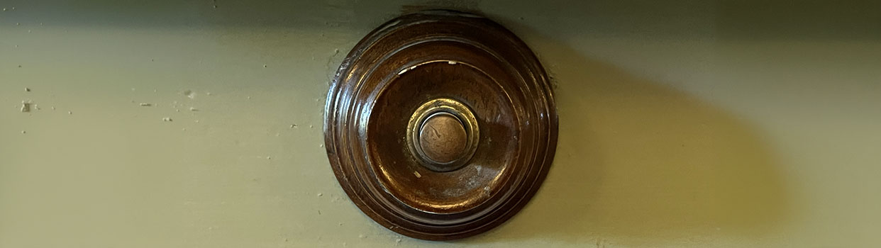 Een ronde houten houder met daarin een ronde drukknop.