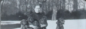 Zwartwit foto van een jonge vrouw met puppy's op schoot