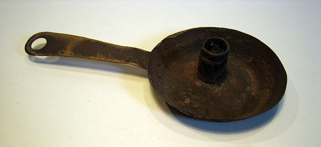 Een kaarsenstandaardje op een ronde lekbak met een steel eraan.