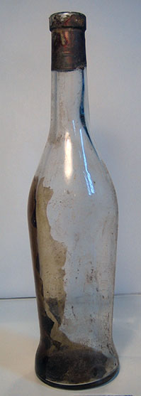 Een langwerpige fles met vuil erin en een rood lood bovenaan de hals