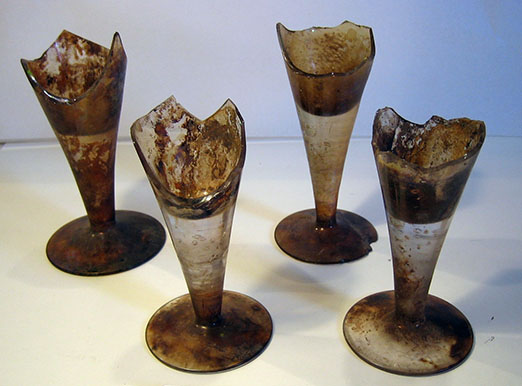 Vier voeten van glazen. De glazen lopenvanuit de voet recht uit in de kelk. De kelken zijn allemaal gebroken. Ze zijn erg vies.