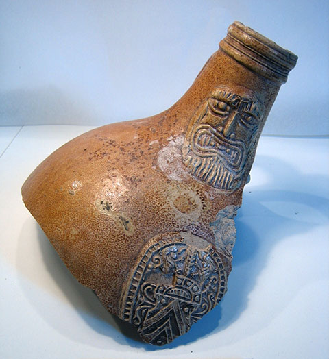 De hals van een kruik met op de hals de kop van een man met een baard