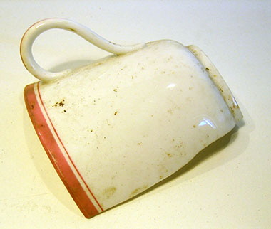 Een half wit kopje met een rode rand en een oor.