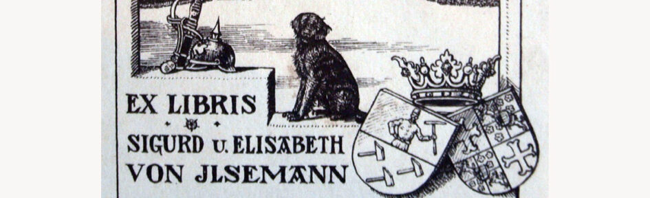 Deel van een exlibris met de tekst: EX LIBRIS * Sigurd u. Elisabeth von Ilsemann. Boven het woord EX LIBRIS ligt een pickelhaube, en trede lager zit een zwarte hond en rechts twee familiewapens met een kroon erboven.