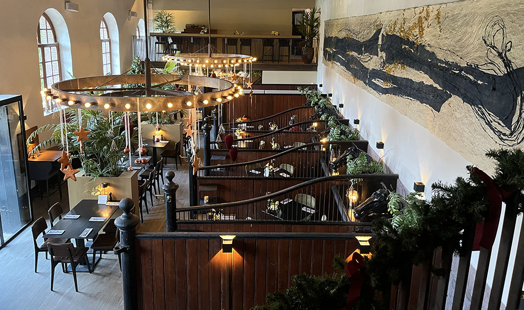 In een grote ruimte staan rechts overdwars losse, halfhoge wanden op de muur. De middelste wandjes het een soort tralies bovenop die hoger zijn naar de muur toe.  De wanden aan beiden uiteinden zijn helemaal van hout en manshoog. De ruimte is ingericht als restaurant en is in kerstsfeer. 