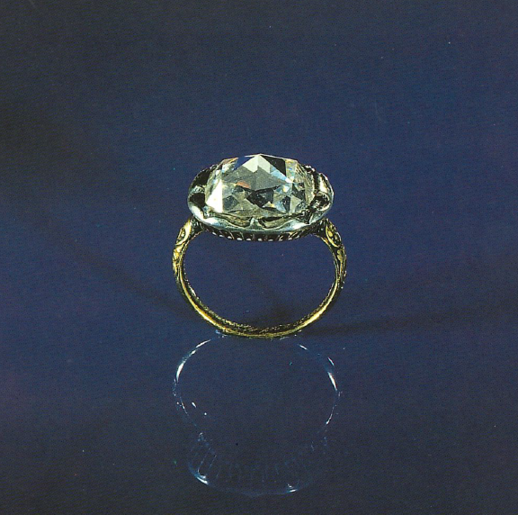 Gouden ring met een grote diamant tegen een blauwe achtergrond.