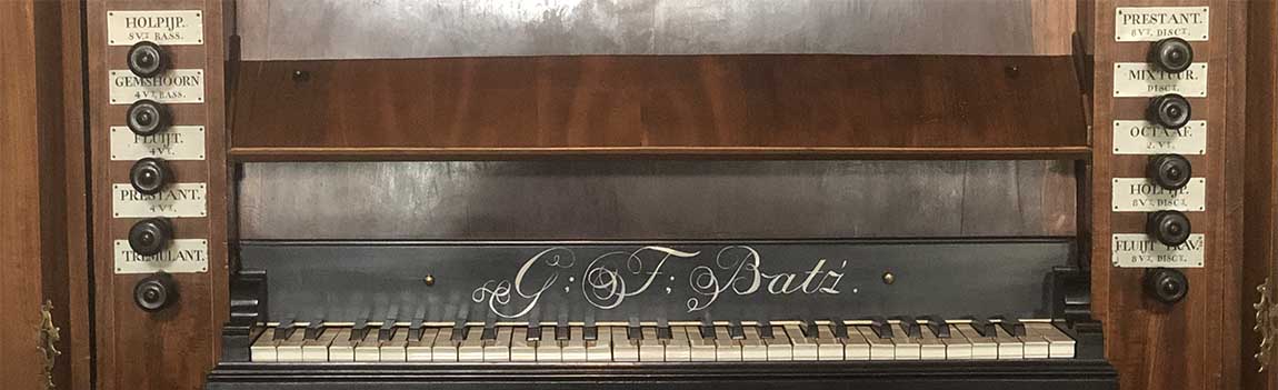 In het midden een klavier met daarboven in sierlijke letters G.F. Bätz. Aan weerszijden ronde knoppen met erboven een plaatje met de naam van het betreffende register.