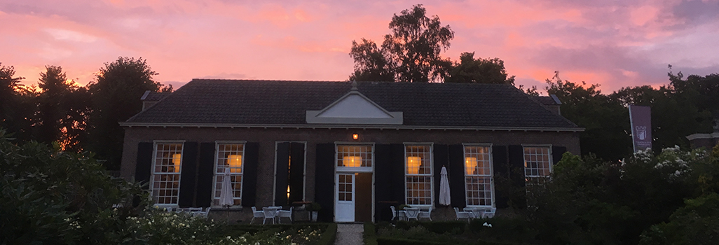De oranjerie in de tuin van Kasteel Amerongen tegen een roze lucht.