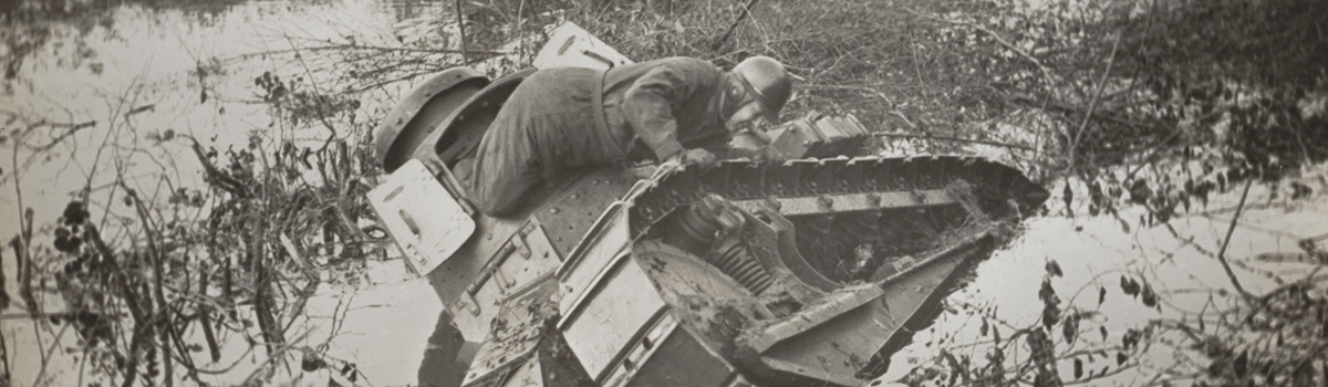 Een soldaat op een tank die half weggezakt is in het water.