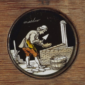'metselaar', met troffel en baksteen in de hand, gebogen over een laag muurtje.