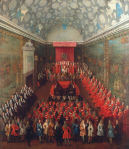 In een lange hoge ruimte met een tongewelf plafond, en schilderijen van schepen op de wanden, zit aan het eind onder een rood baldakijn met daarop een wapen de koningin io haar troon. Om haar heen staan diverse mannen en vrouwen. Aan de rechter zijde zitten twee rijen met heren met rode mantels aan met daarop horizontale strepen. In het midden in een vierkant zitten acht heren in het zwart. Aan deze kant van de korte zijde zitten nog vijf rijen met heren met dezelfde rode mantels. Aan de linker kant een hoge schouw en aan deze kant twee rijen met eren met een witte blouse met daaroverheen iets zwart. Helemaal op de voorgrond diverse heren met pruiken in elegante dagelijkse kleding.