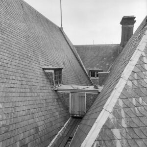 Ruimte tussen drie daken: links gaat een zadeldak omhoog, rechts ook, aan het eind zit ook een zadeldak. Rechts op de aansluiting tussen de daken staat een schoorsteen, links aan het eind ligt een trap tegen het dak naar de vlaggenmast. De daken zijn gedekt met leien, op de ribben van de daken en op de aansluitingen tussen de daken ligt lood, tussen de daken zit een dakgoot, op verschillende plekken zitten ramen in de daken. Tussen het dak links en rechts is een smalle doorgang met daarin een luik.