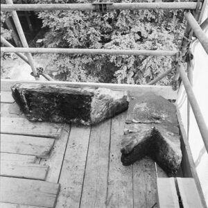 Zwartwitfoto van een steiger met daarop twee grote (bijna drie planken breed) stukken steen.