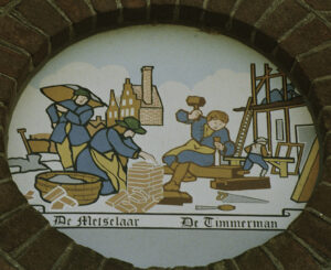 In een ovaal zijn verschillende mensen aan het werk. Helemaal links een man met een zak op zijn schouder, voor hem een geknielde man naast een ton met morel die een muurtje metselt. Daarnaast die op een balk zit waarin hij een beitel slaat en daarachter een man die met een kozijn bezig lijkt te zijn. Op de achtergrond een gemetseld huis met een hoge schoorsteen en het houten skelet van een huis in aanbouw.