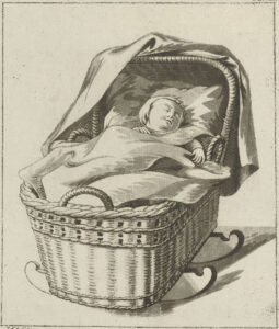 In een rieten wiegje ligt een baby te slapen, de handjes boven de dekens. Op de kap ligt een doek.
